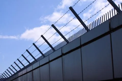 Safety wall with barbed wire and spikes on top of a fence provide security Foto stock