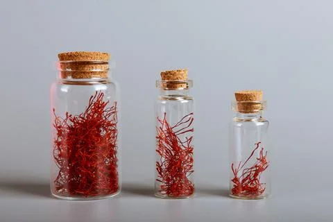 Saffron stamens in jars of one, two and five grams on a white background. Stock Photos