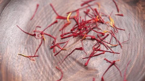Saffron threads falling onto a rustic wooden surface Stock Footage 337413262