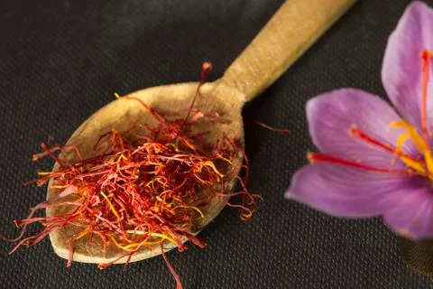 Saffron types in a spoon and saffron flower on a black background Stock Photos