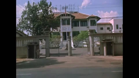 SAIGON - 1962 - A sentry stands with a rifle at the MAAG gate as workers build a Video stock 322761346