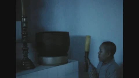 SAIGON - 1969: Buddhist rite - A monk strikes a large temple drum Vídeo Stock 343937155