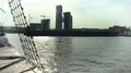 Sail boat approaching shipping platform, office buildings under construction HD Footage