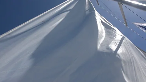 The sail of a yacht waves in the wind and then stretches Stock Footage