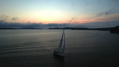 A sailboat floats on the water surface at sunset, footage taken from the air Stock Footage 245471996