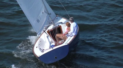 Sailboat at full sail with a man and woman aboard on a sunny day Stock Footage 1077295