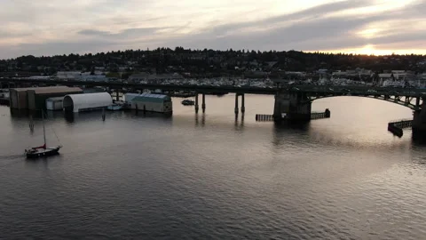 Sailboat in harbor approaching draw bridge with sunset Stock Footage 169540596