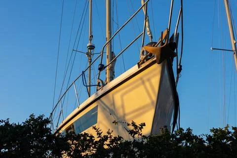Sailboat moored at dock, casting shadows in sunset Stock Photos