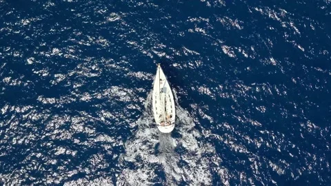 Sailboat navigates through deep blue ocean waters, creating white frothy waves Stock Footage 345155575