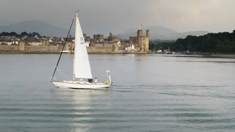 Sailboat navigating in front of Caernarfon Castle in Wales Stock Footage 336756647