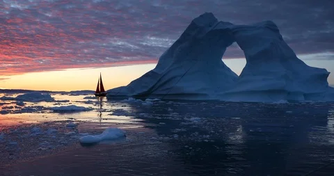 Sailboat next to a massive iceberg with a hola at sunrise. Stock Footage 100590024