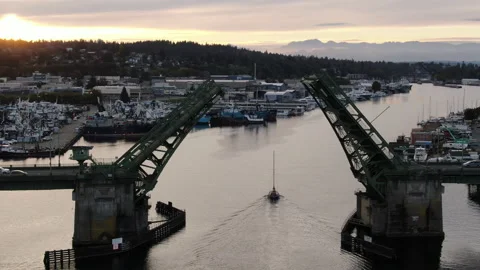 Sailboat passes through drawbridge with sunset in background Stock Footage 169540871