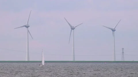 Sailboat sailing in front of wind turbines and power lines Stock Footage