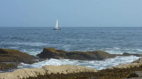 A sailboat sailing over the waves along the coast of Maine pulling a small Stock Footage 325786173
