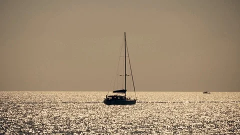 Sailboat in the sea in the rays of the sunset sunlight. Silhouette of a sailboat Vídeo Stock 107855045