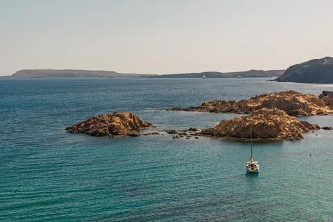 Sailboat stranded on the shore next to several rock formations Stock Photos