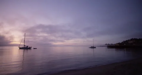 Sailboats float along the shore during early morning sunrise Stock Footage 169001063