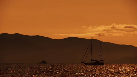 A sailing boat floats along the waves in the orange light of the evening sunset Stock Footage 92205490