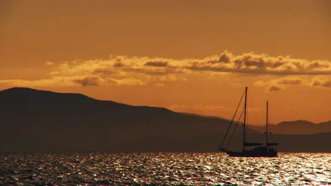 A sailing boat floats along the waves in the orange light of the evening sunset Stock Footage 92205530