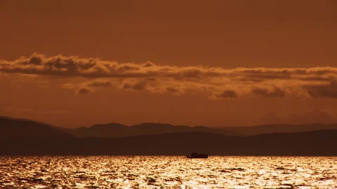 A sailing boat floats along the waves in the orange light of the evening sunset Stock Footage 92205585