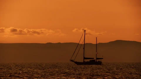 A sailing boat floats along the waves in the orange light of the evening sunset Stock Footage 92205628