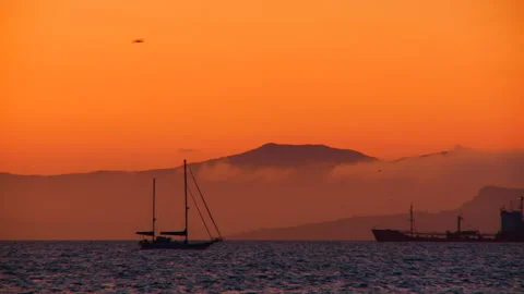 A sailing boat floats along the waves in the orange light of the evening sunset Stock Footage 92206033