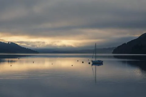 Sailing boat under dramatic sunset sky on Loch Tay Lake at sunset, Kenmore, Stock Photos