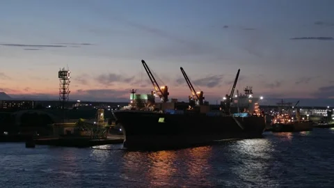 Sailing by cargo ship with loading cranes on deck and sunset color in sky Stock Footage 254453946