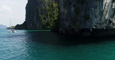 Sailing catamaran dwarfed by a sheer limestone wall Stock-Footage 71297469