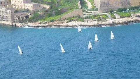 Sailing dinghies race close together fort manoel walls rising behind them on Stock Footage 341805209