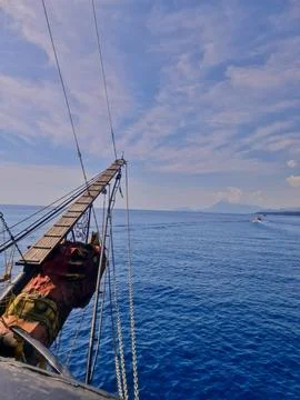 Sailing Ship Bow Over Deep Blue Sea and Distant Island Stock Photos