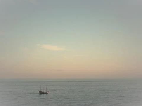 Sailing ship navigating calm ocean under sunset sky Stock Photos