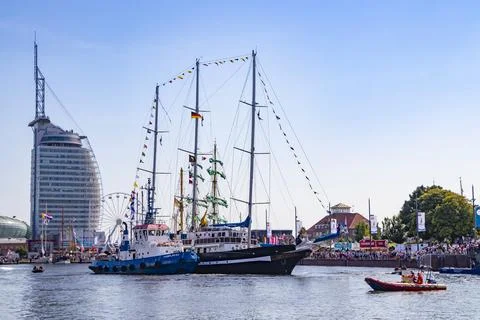 A sailing ship is pushed to its berth by a tugboat for the Sail Event in Br.. Stock Photos