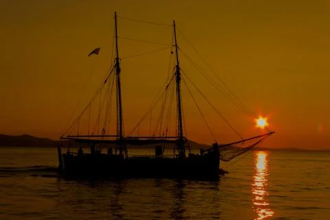 Sailing into the sunset with reflections on the sea surface Stock Photos