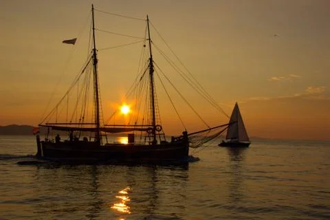 Sailing into the sunset with reflections on the sea surface Stock Photos