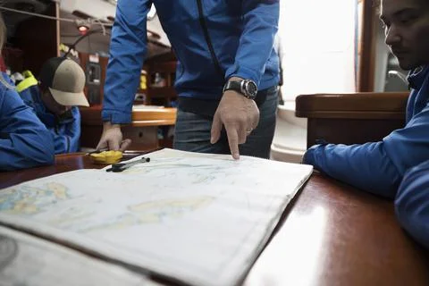 Sailing team plotting course at map on sailboat Fotos de archivo