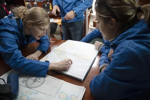 Sailing team plotting course at map on sailboat Fotos de archivo
