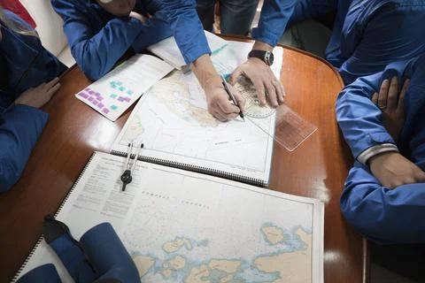 Sailing team plotting course at map on sailboat Fotos de archivo