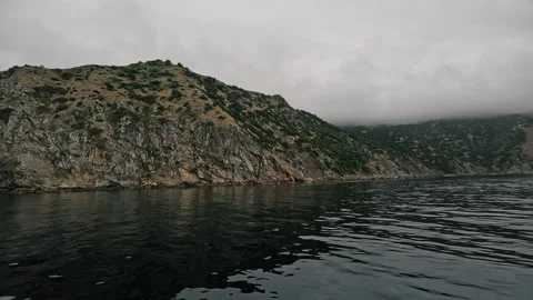 Sailing through calm waters along the cliffs and mountains of a small island  Stock Footage 278831323