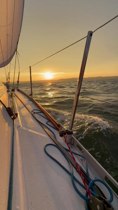 Sailing through calm waves during a golden sunset on the Baltic Sea Stockbeeldmateriaal 320939830
