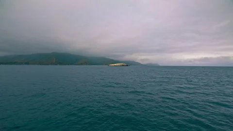 Sailing through the ocean under low-hanging rain clouds, towards the mountains Stock Footage 278831923
