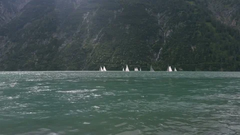 Sailing on the waves in lake between the mountains in the cloudy day Stock Footage 81935628