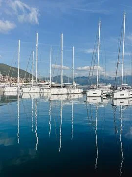 Sailing yachts with high masts reflected in the sea against the backdrop of a Stock Photos