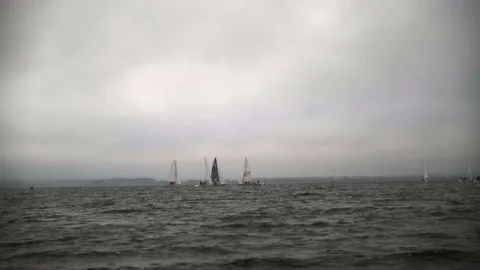 Sailing yachts sail on the waves in a cloudy windy lake Stock Footage 219958857