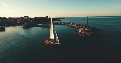 Sailingboat leaving harbour at sunset backlight seagul flying around aerial Stock Footage 153499351