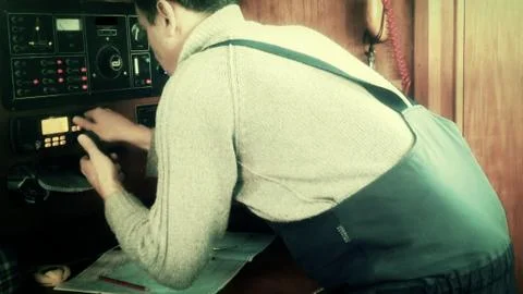 Sailor at chart table during storm about to make radio call Foto stock