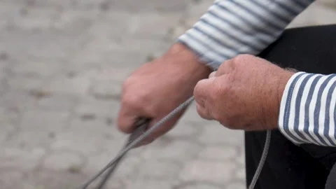 Sailor fisherman sharpening knife using length of rope Stock Footage 289449895