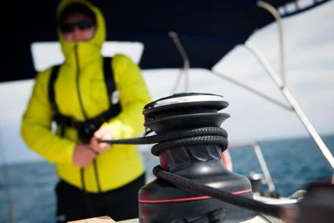 Sailor jacket pulls the rope winch on sailing yacht Stock Photos