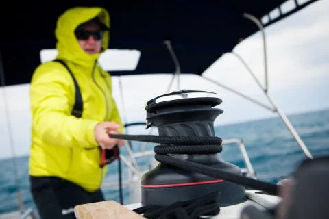 Sailor jacket pulls the rope winch on sailing yacht Stock Photos