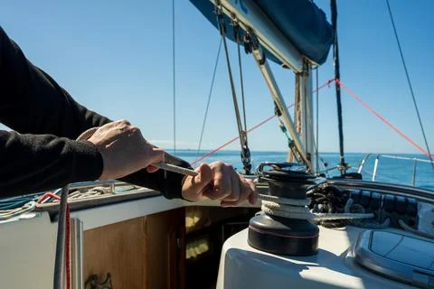 Sailor pulling rope on sailboat winch during navigation Stock Photos